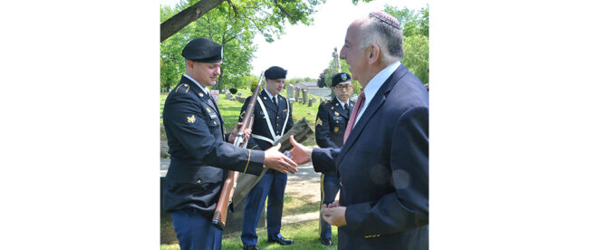 Army Spc. William Armstrong, a New York Army National Guard Soldier assigned to the 107th Military Police Company, receives a challenge coin from retired U.S. Navy Chaplain (Capt.) Rabbi Irv Elson, representing the Jewish Welfare Board Jewish Chaplains Council, in appreciation of his support as a color guard for the remembrance ceremony of Union Sgt. Benjamin Levy at his burial site at Cypress Hills Cemetery in Brooklyn, N.Y., May 21, 2021. Levy was a New York Soldier who is the first Jewish American to receive the Medal of Honor for his actions to save his regimental colors and rally his unit, the 1st New York Volunteer Infantry Regiment, during the Battle of Glendale in June 1862. (U.S. National Guard photo by New York Guard Capt. Mark Getman)