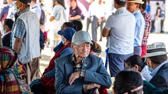 an elderly man sitting among crowd of people